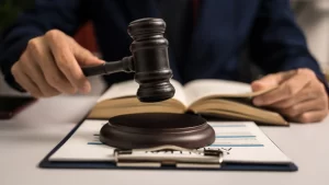 Judge striking gavel on desk with an open book in the background.
