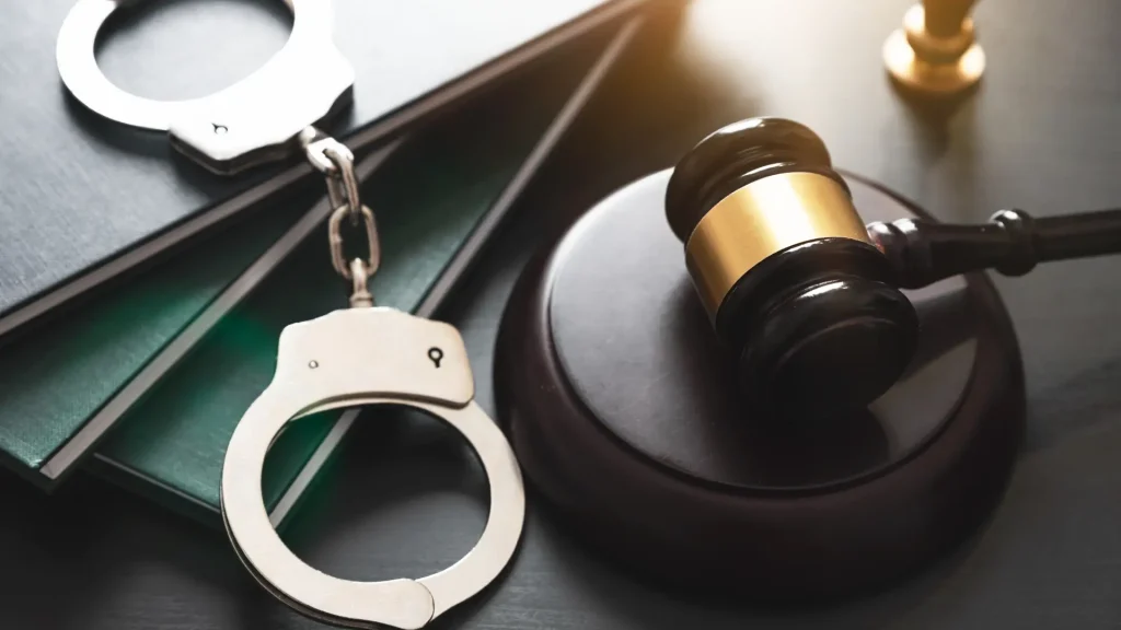 Handcuffs and a gavel on a legal desk.