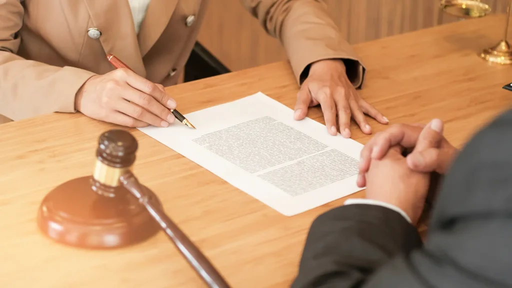 Lawyer reviewing a legal document with a client at a desk with a gavel nearby.